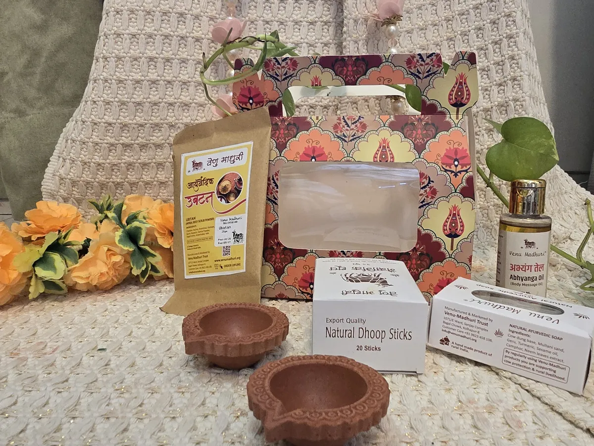 Printed gift box with ubtan, abhyanga oil, ayurvedic soap, dhoop sticks and two clay diyas laid out in front