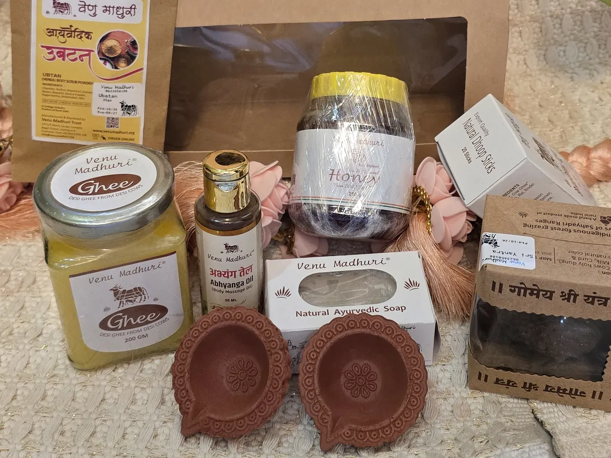 Kraft gift box behind ghee, honey, ubtan, abhyanga oil, soap, Gomay Sri Yantra, dhoop sticks and two clay diyas